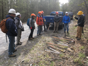 Trail workshop attendees viewing trail building tools in forest setting.